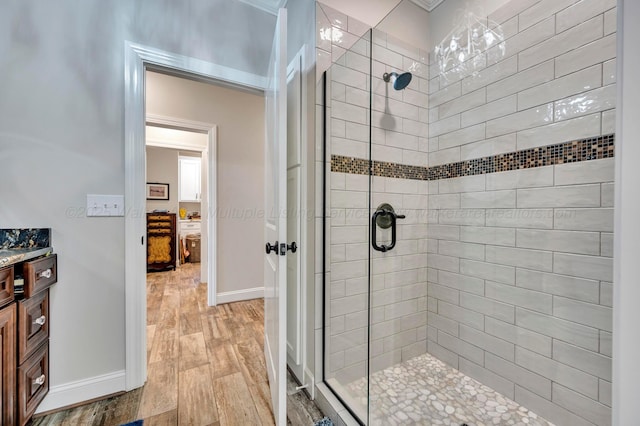 bathroom with vanity, baseboards, wood finished floors, and a stall shower