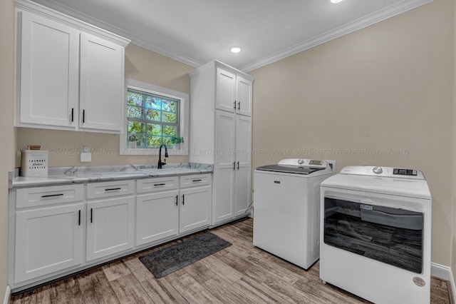 washroom featuring crown molding, washing machine and dryer, light wood-type flooring, cabinet space, and a sink