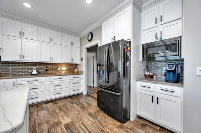 kitchen featuring decorative backsplash, crown molding, wood finished floors, white cabinets, and stainless steel appliances