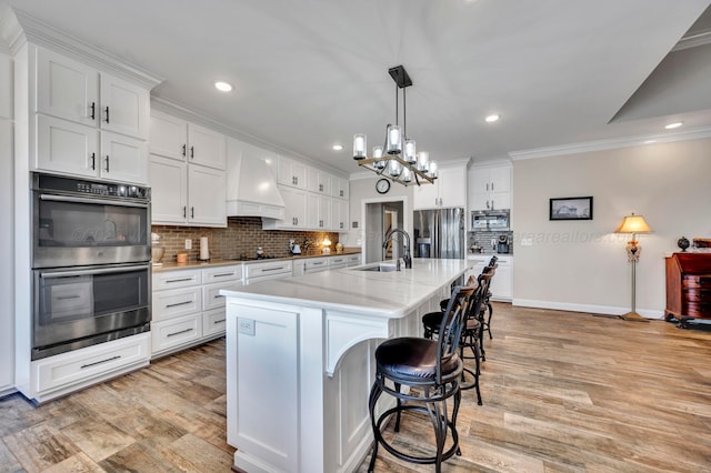 kitchen featuring a sink, premium range hood, stainless steel appliances, tasteful backsplash, and ornamental molding