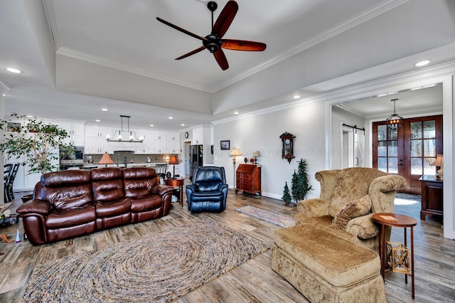 living area featuring crown molding, wood finished floors, baseboards, recessed lighting, and ceiling fan with notable chandelier