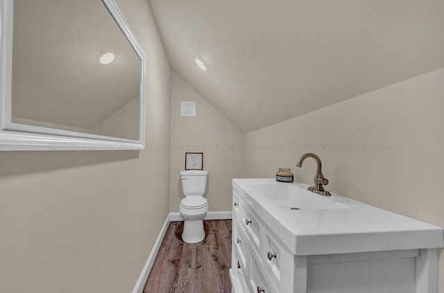 bathroom featuring vaulted ceiling, wood finished floors, vanity, baseboards, and toilet
