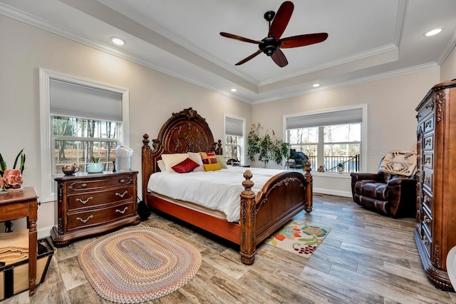 bedroom with recessed lighting, ornamental molding, wood finished floors, and a tray ceiling
