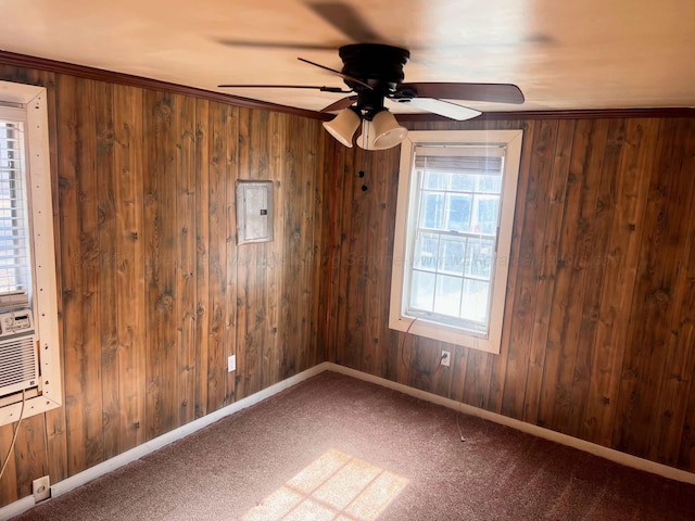 carpeted spare room with ornamental molding, electric panel, wooden walls, and ceiling fan