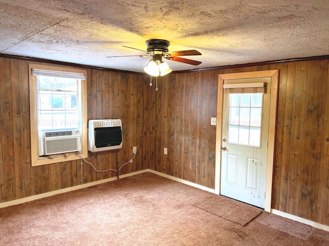 carpeted empty room with ceiling fan, cooling unit, wooden walls, heating unit, and a textured ceiling