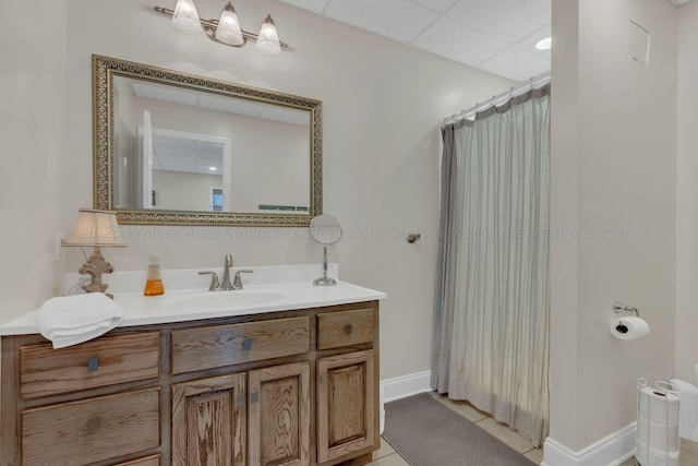 bathroom with tile patterned floors, a shower with shower curtain, vanity, baseboards, and a drop ceiling