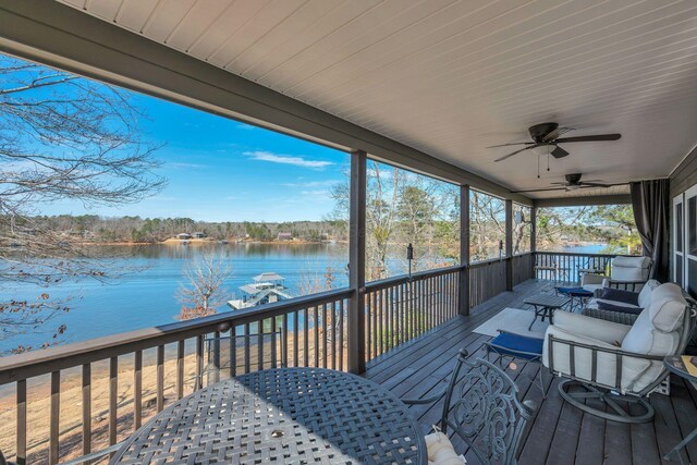 wooden terrace featuring a water view, outdoor dining space, and a ceiling fan