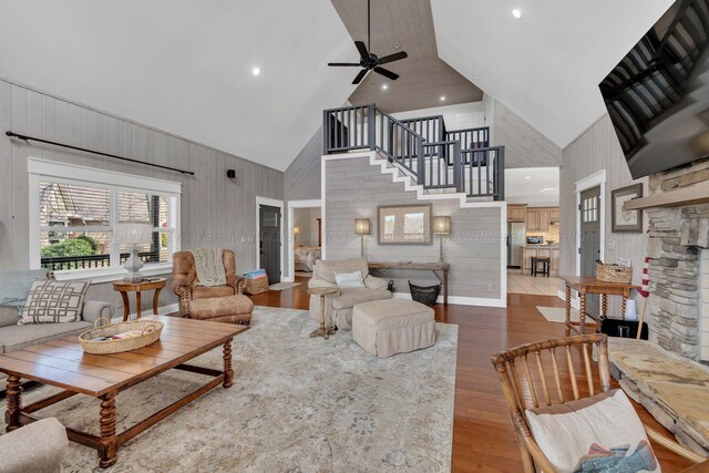 living room with stairs, high vaulted ceiling, wood finished floors, and a ceiling fan