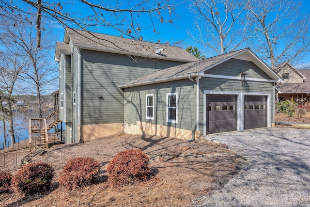 view of side of property with driveway, a garage, and roof with shingles