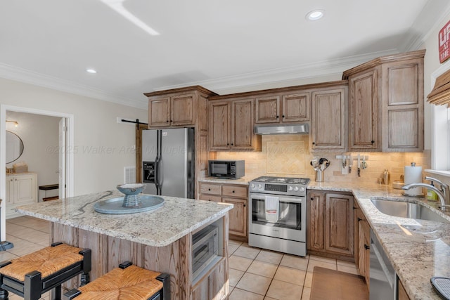 kitchen with a sink, appliances with stainless steel finishes, under cabinet range hood, light tile patterned floors, and ornamental molding
