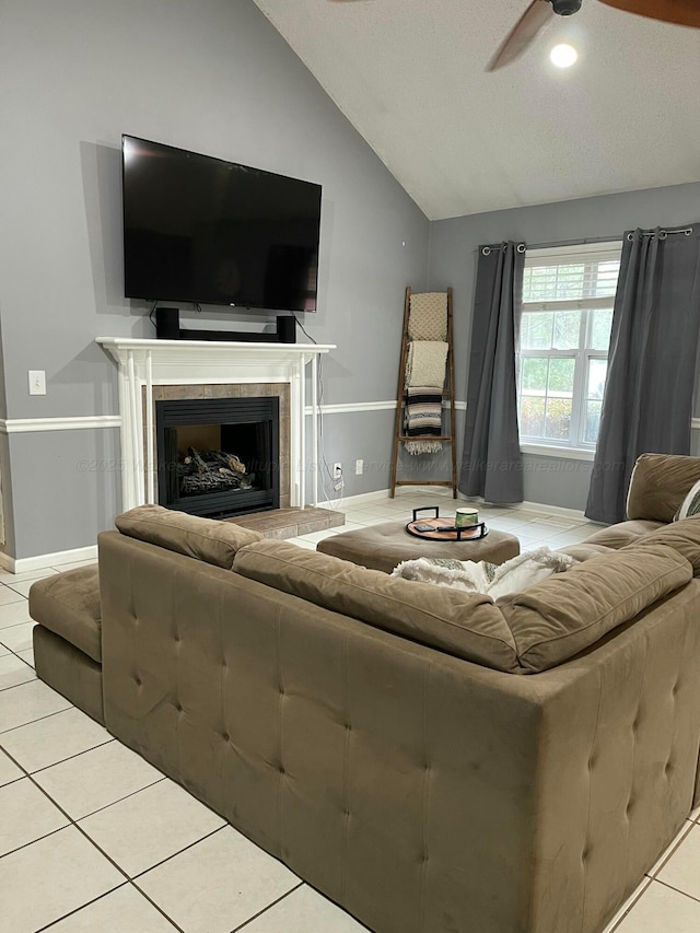 living room with a ceiling fan, lofted ceiling, tile patterned flooring, a fireplace, and baseboards