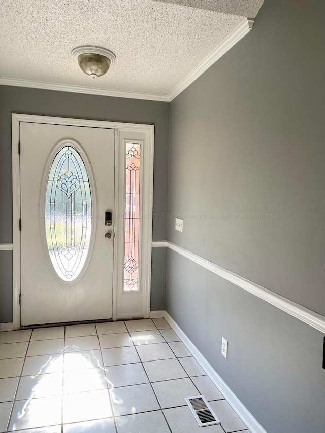 entrance foyer featuring light tile patterned floors, a textured ceiling, baseboards, and ornamental molding