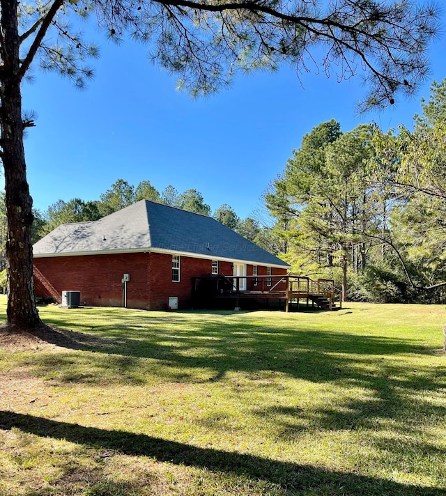 view of grassy yard with a wooden deck and central AC