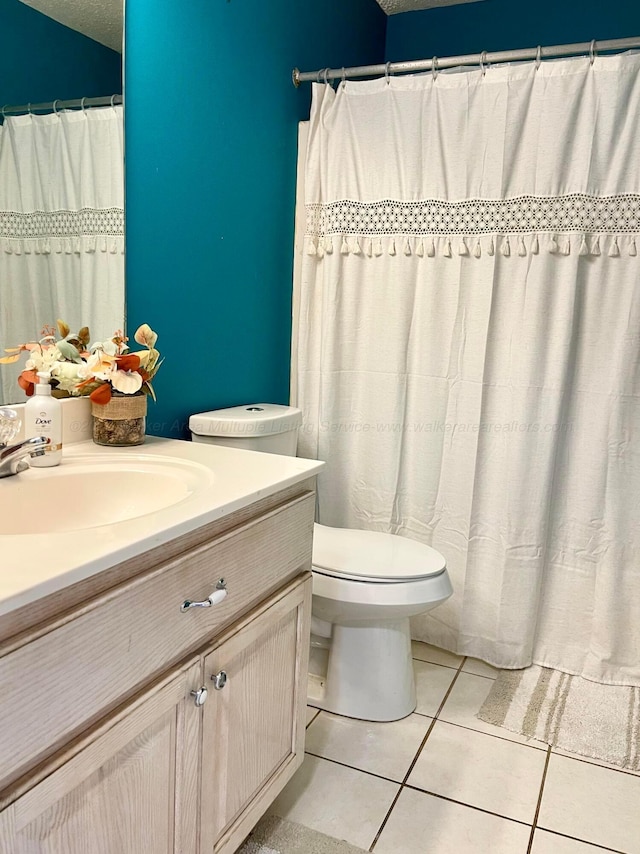 bathroom featuring tile patterned floors, vanity, toilet, and a textured ceiling
