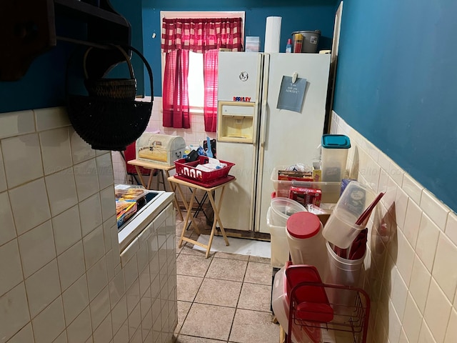kitchen with washer / clothes dryer, tile walls, wainscoting, white refrigerator with ice dispenser, and tile patterned flooring