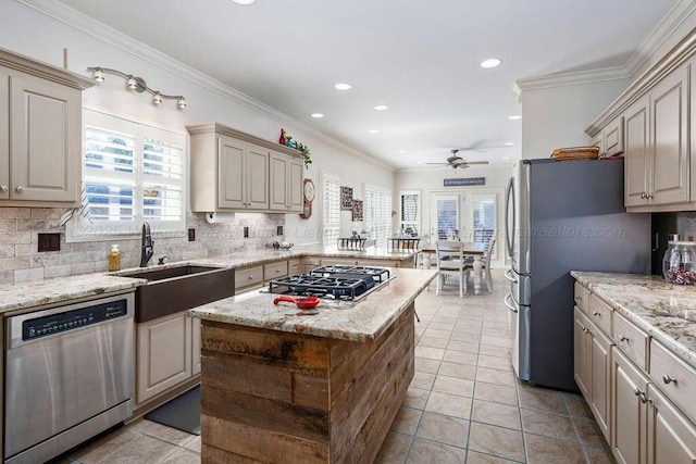 kitchen with tasteful backsplash, appliances with stainless steel finishes, ornamental molding, a peninsula, and a sink