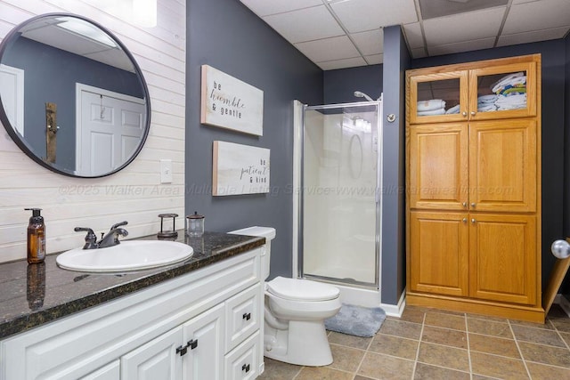 full bathroom featuring a paneled ceiling, a shower stall, toilet, and vanity