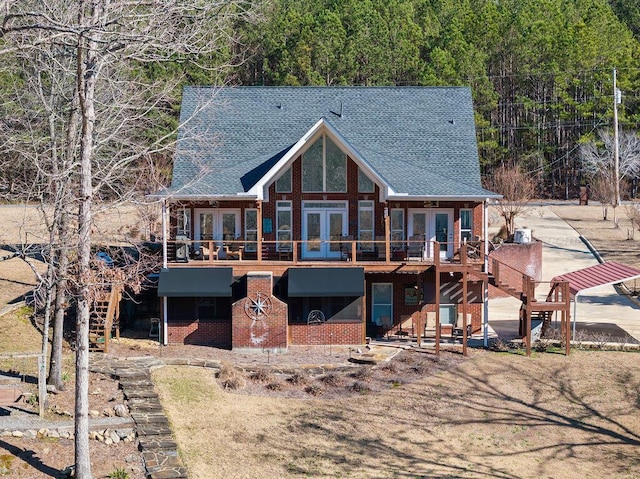 back of house with a deck, a shingled roof, brick siding, stairs, and french doors