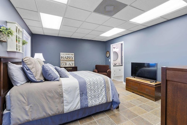 bedroom featuring a drop ceiling, visible vents, and ensuite bath