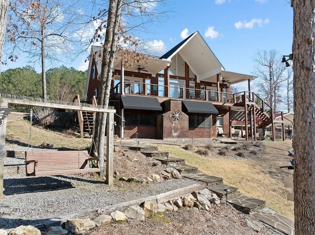 exterior space featuring a ceiling fan, brick siding, and stairs