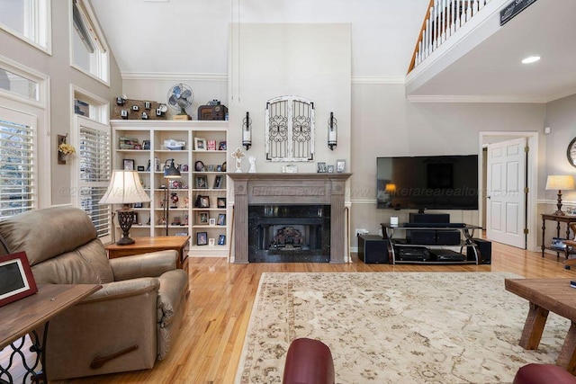 living room featuring a fireplace, crown molding, a high ceiling, and wood finished floors