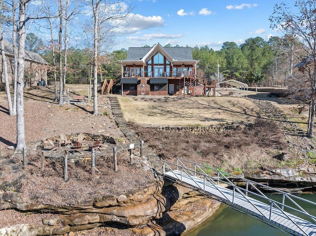 rear view of house featuring a deck with water view and stairs