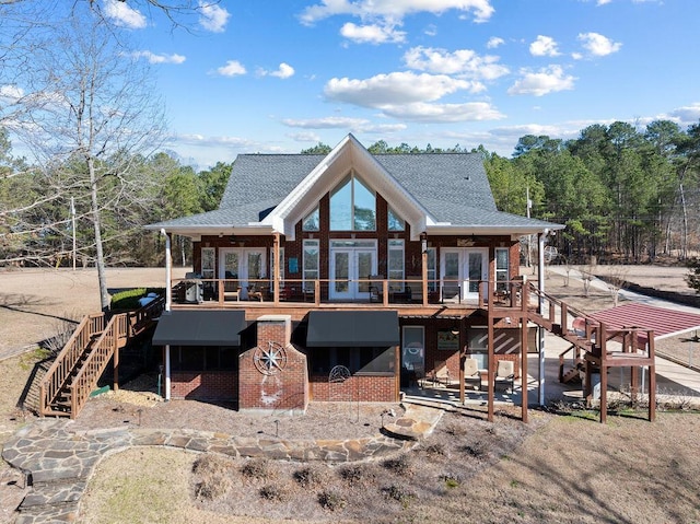 rear view of property featuring stairs, french doors, a shingled roof, and brick siding