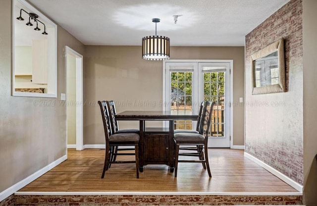 dining space featuring wood-type flooring and a textured ceiling