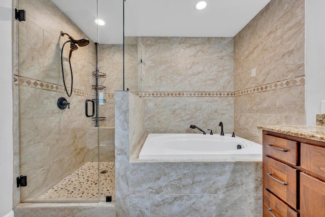 bathroom with shower with separate bathtub, vanity, and tile walls