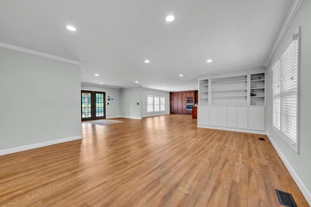 unfurnished living room with light wood-type flooring, crown molding, and french doors