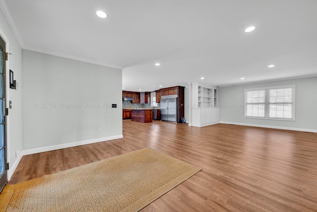 unfurnished living room with wood-type flooring and crown molding