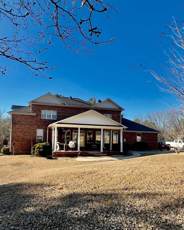 rear view of house with brick siding and a lawn