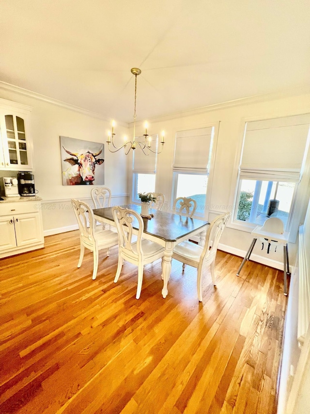 dining space featuring a chandelier, ornamental molding, and light wood-type flooring