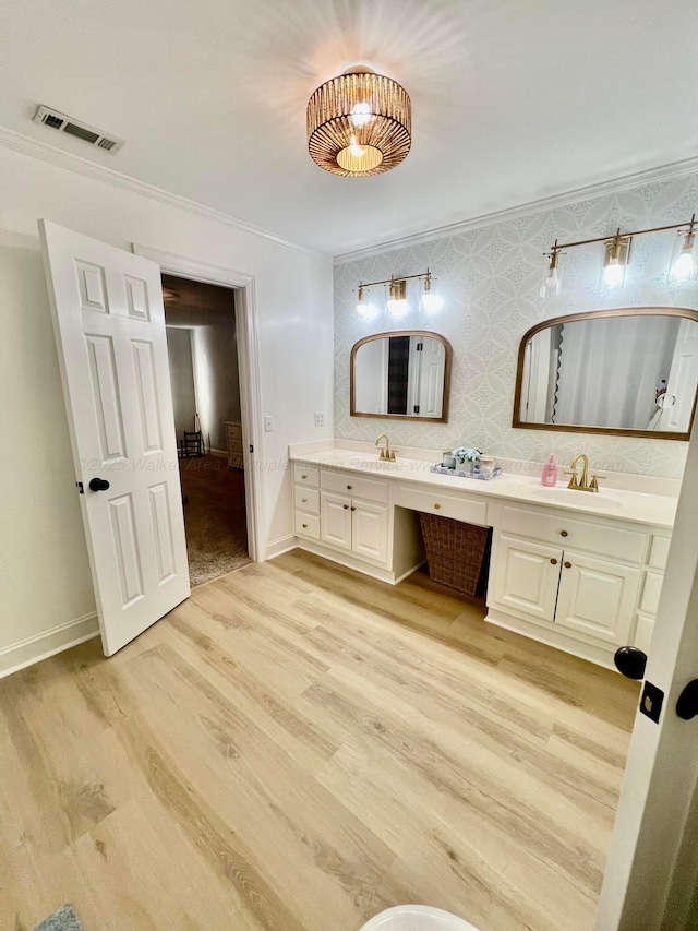 full bath with double vanity, visible vents, a sink, and wood finished floors