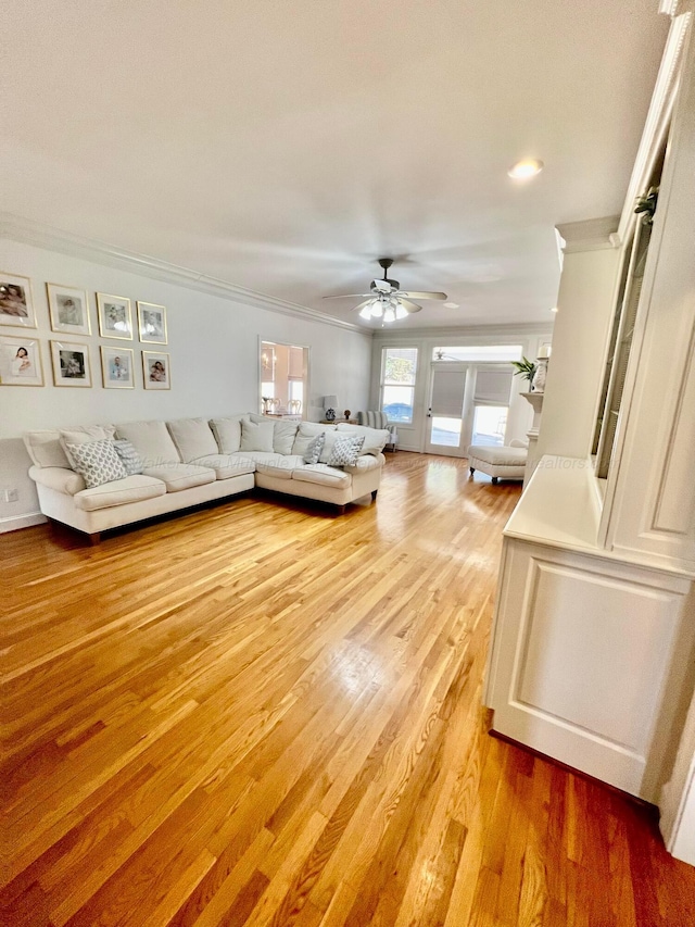 living room featuring crown molding, a ceiling fan, and light wood-style floors