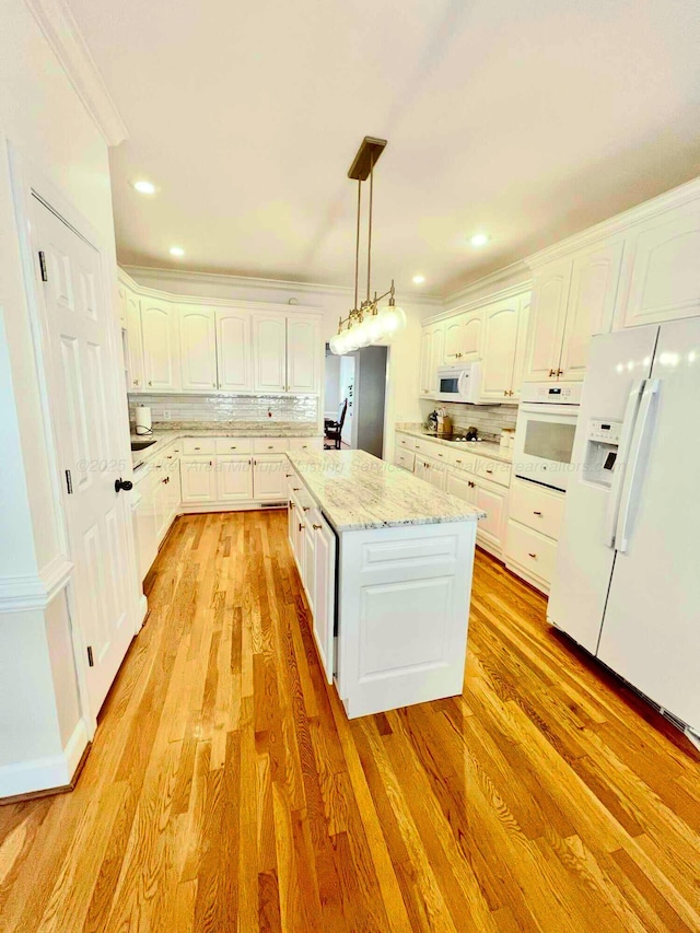 kitchen featuring white appliances, white cabinetry, backsplash, and a center island