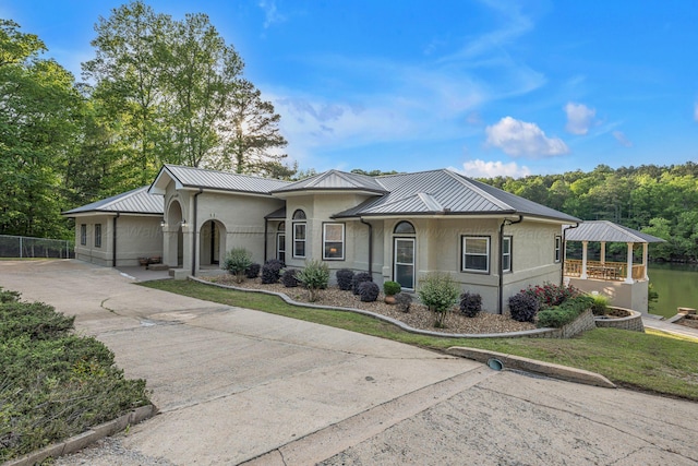 view of front of home with fence, stucco siding, a standing seam roof, metal roof, and a gazebo
