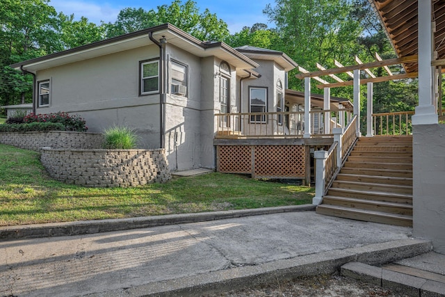 view of property exterior featuring stairway, a deck, a yard, and stucco siding