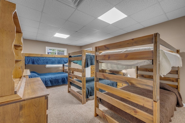 carpeted bedroom featuring a drop ceiling