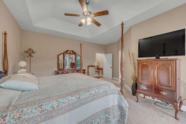 bedroom with baseboards, a ceiling fan, a raised ceiling, and light carpet