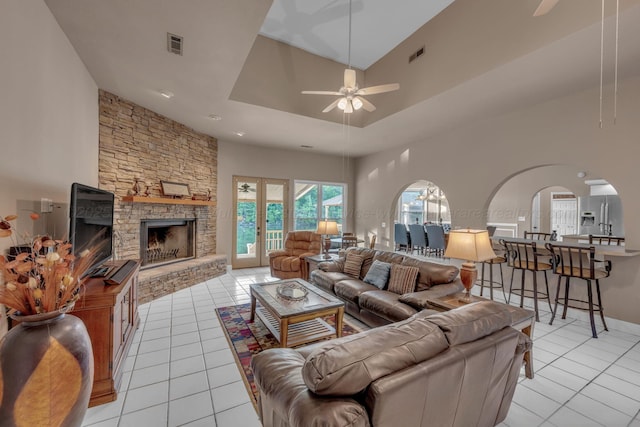 living room featuring light tile patterned floors, arched walkways, ceiling fan, and visible vents
