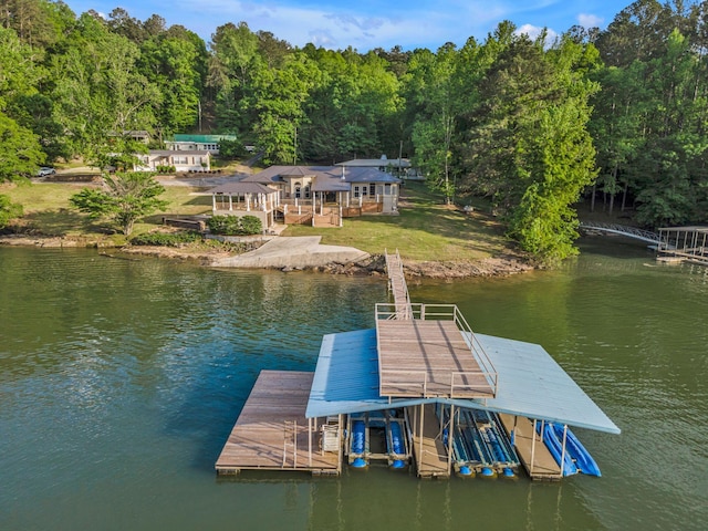 dock area featuring a lawn, a water view, and a wooded view