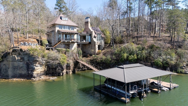 view of dock featuring boat lift, a wooded view, a water view, and stairway