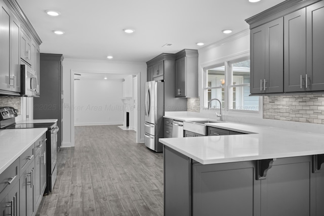kitchen featuring light countertops, light wood-type flooring, ornamental molding, stainless steel appliances, and gray cabinetry