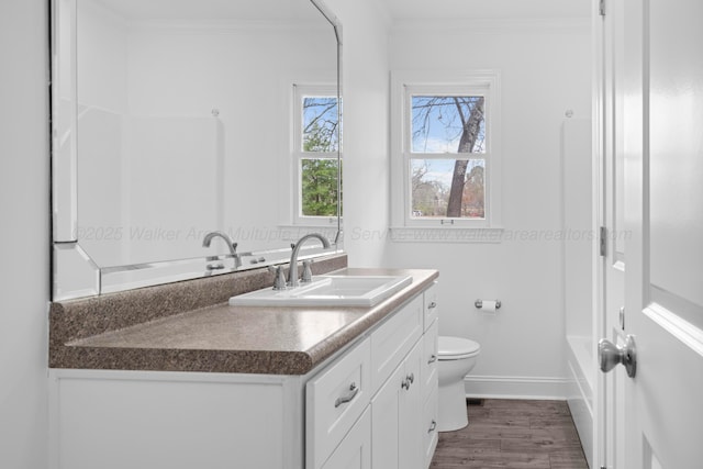 full bath featuring crown molding, baseboards, toilet, wood finished floors, and vanity