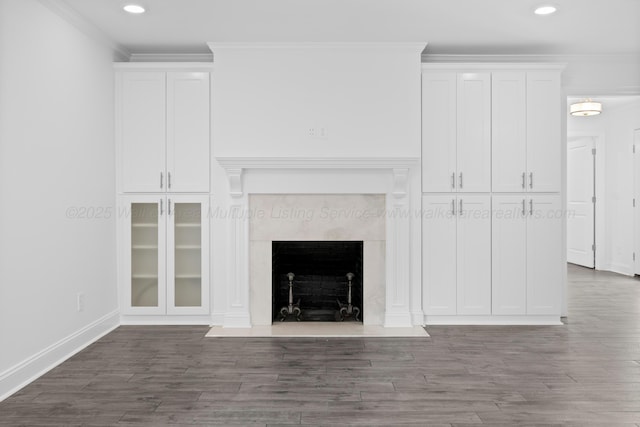 unfurnished living room with recessed lighting, ornamental molding, baseboards, a fireplace, and wood finished floors