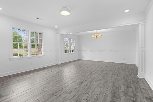 empty room with crown molding, a chandelier, baseboards, visible vents, and dark wood-style flooring