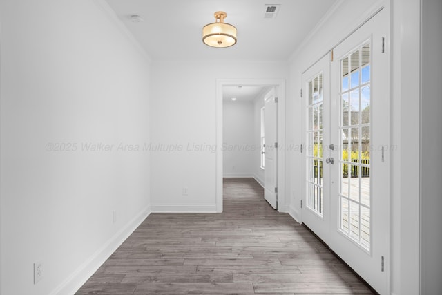 entryway with baseboards, visible vents, crown molding, and wood finished floors