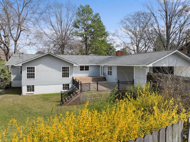 back of property with roof with shingles, a chimney, a wooden deck, an attached garage, and a yard