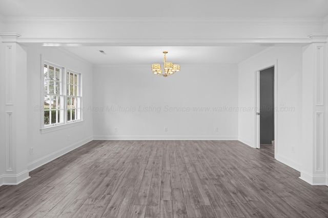 unfurnished room featuring an inviting chandelier, ornamental molding, baseboards, and wood finished floors